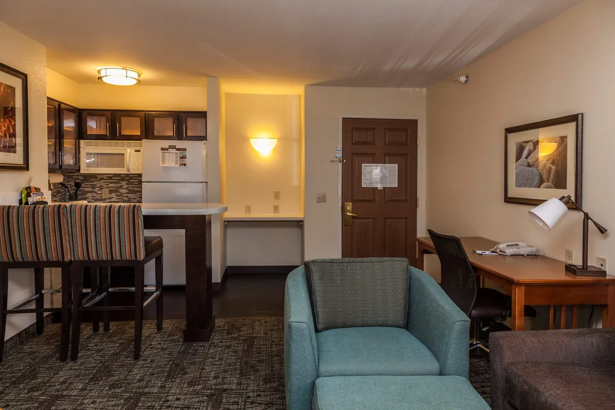 The image showcases a bright, inviting interior featuring a well-equipped kitchenette with sleek bar stools, a cozy seating area for relaxing, and a dedicated desk space for work or planning adventures. The overall ambiance is warm, functional, and perfect for both relaxation and productivity.