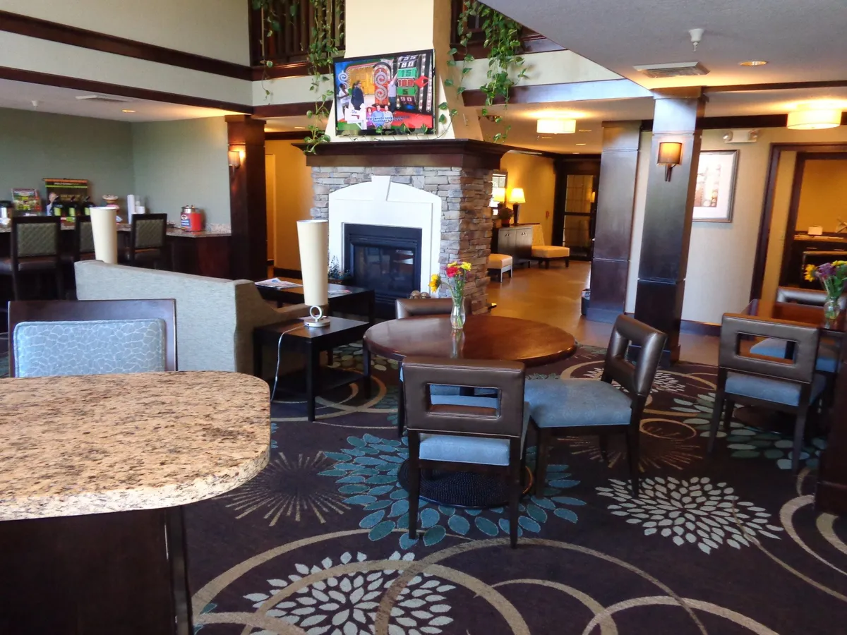 A stylish interior living area with a fireplace as the focal point, complemented by colorful artwork and tasteful decorative table arrangements. The space is designed for socializing, reading, or unwinding in a warm, homey environment.